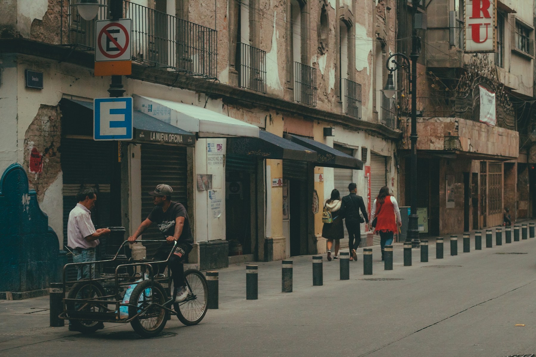 Personas caminando y un ciclista en una calle del Centro Histórico de la Ciudad de México
